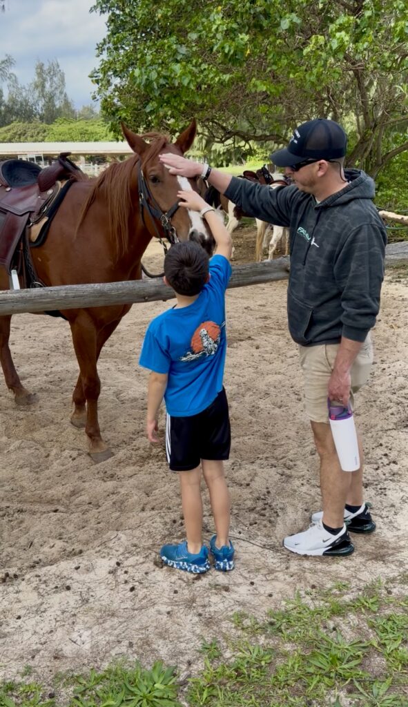 father and son petting a horse at The Ritz-Carlton Oahu, Turtle Bay